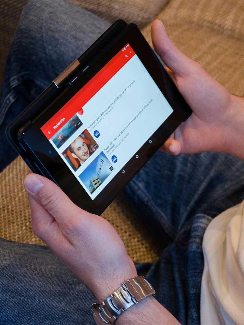 A photo of a man holding a tablet watching videos