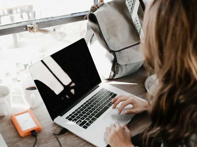 Close-up Photography of Woman Sitting Beside Table While Using Macbook